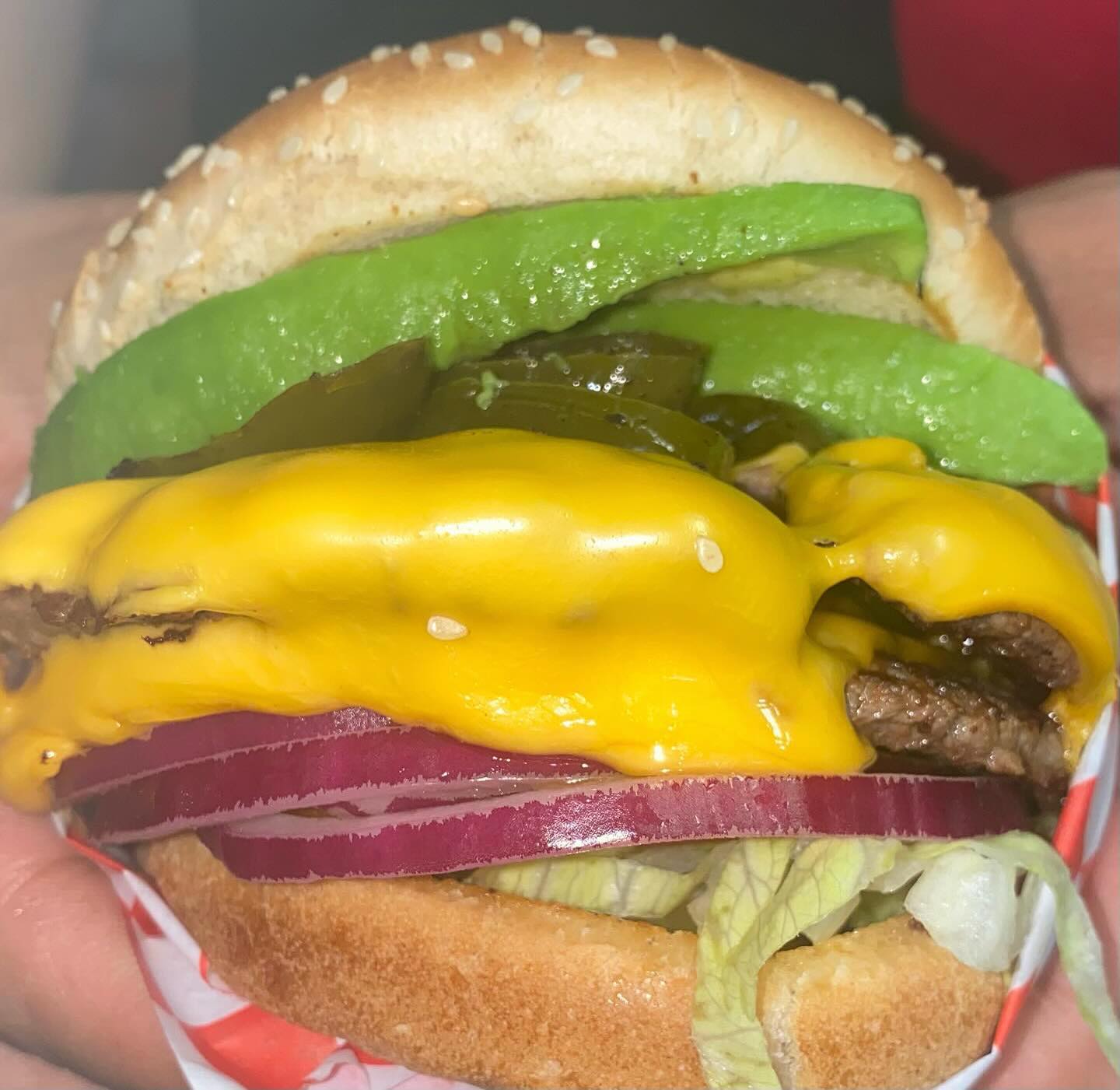 Avocado jalapeno cheeseburger with red onion and melted cheese